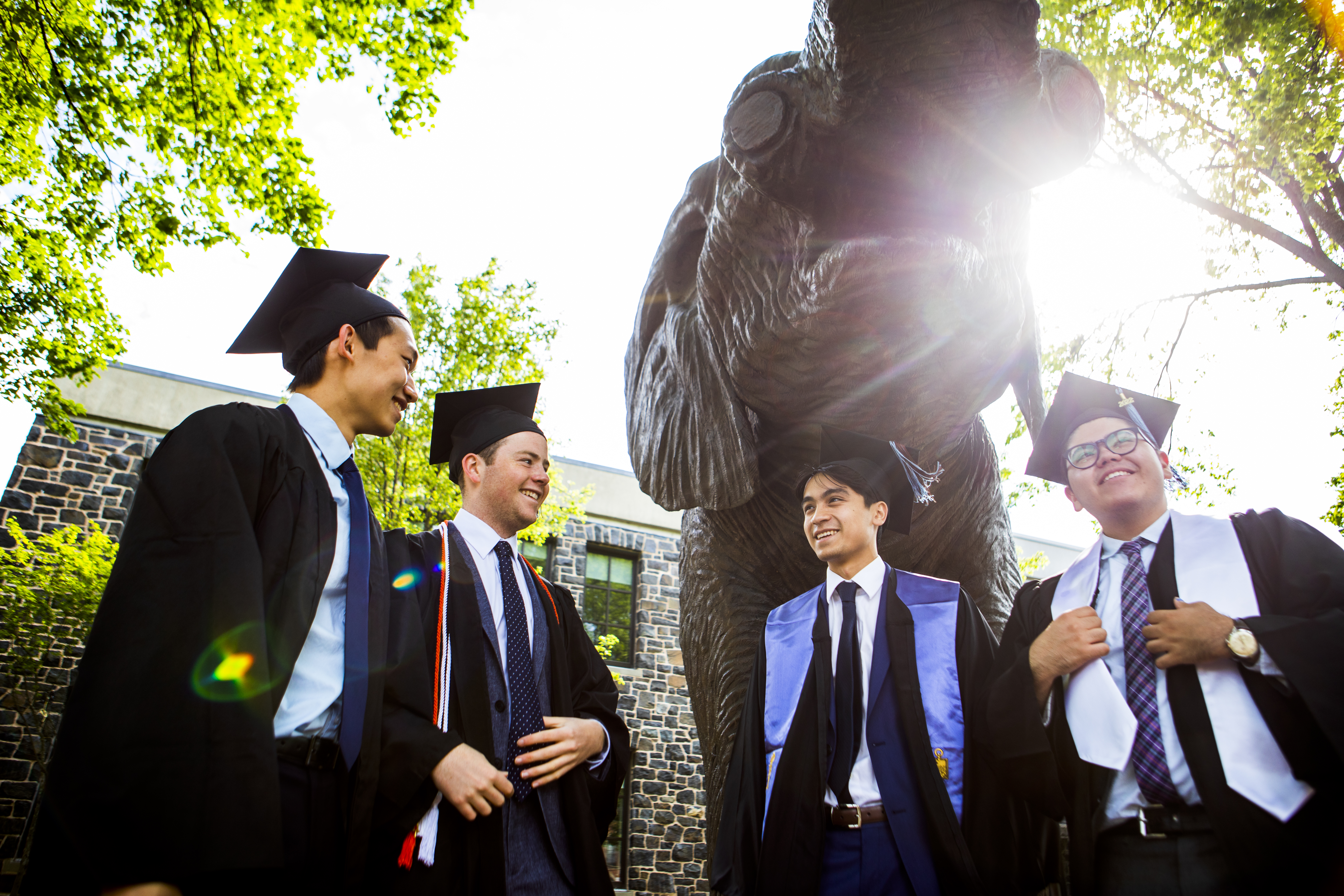 Students celebrating graduation in front of Jumbo statue.